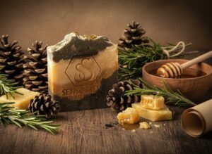 Pine tar bar soap made with Canadian beeswax, honey, rosemary, cedarwood oil, and natural botanicals, displayed with pine cones and dried calendula buds by Sensosalve in Richmond, BC